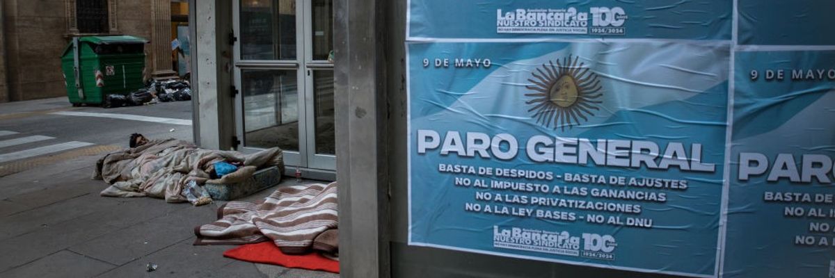 A family sleeps in front of a closed office building in Buenos Aires