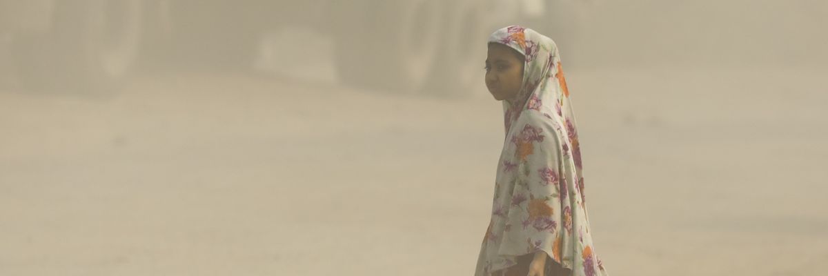 A girl walks on a heavily polluted road 