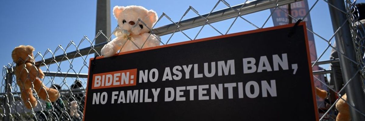 A sign and teddy bears are tied to a fence as immigrant rights organizations rally 