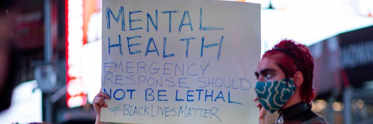 A sign protests lethal responses to mental health emergencies. 