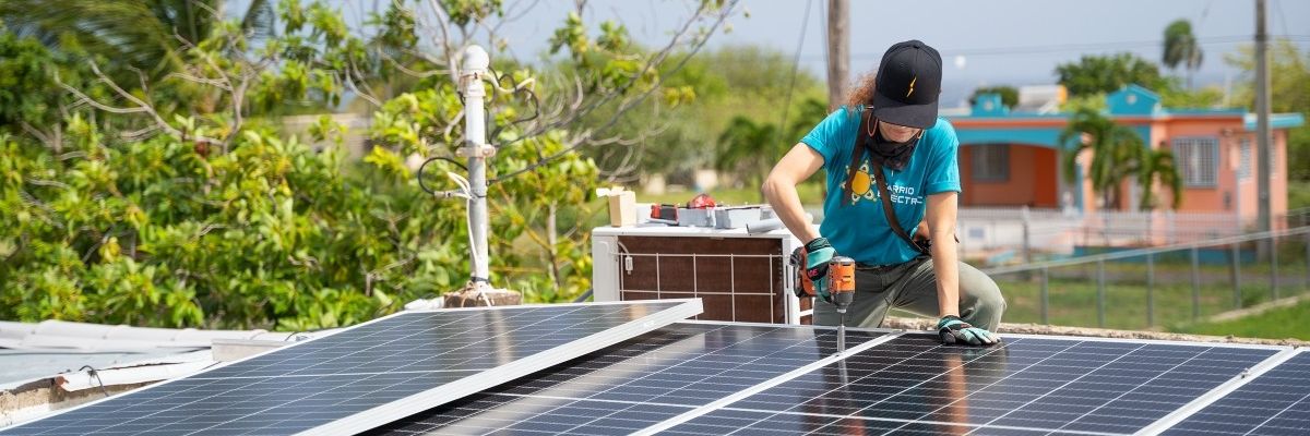 A woman installs a rooftop solar panel in Puerto Rico