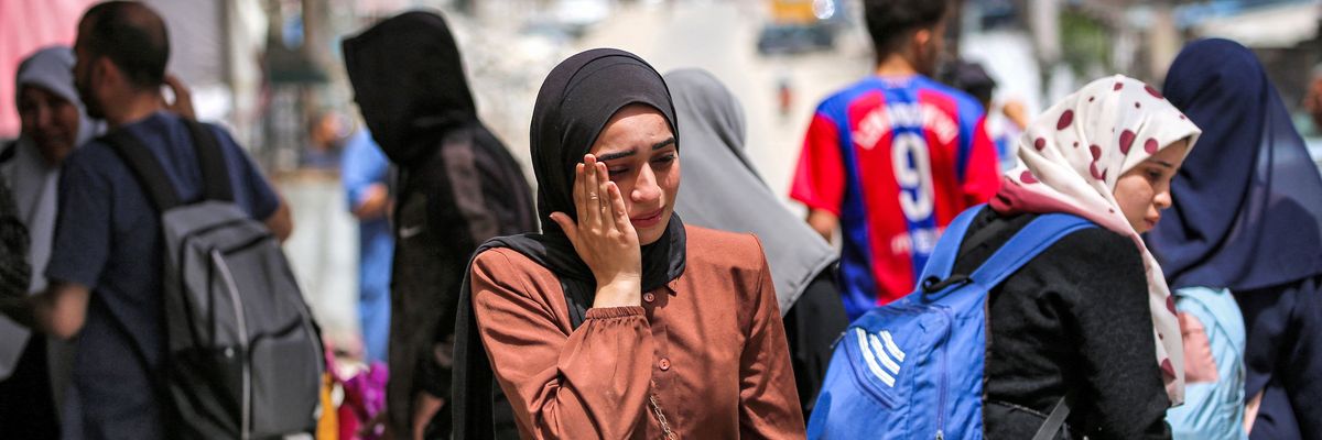 A woman reacts as she waits with others before evacuating from Rafah