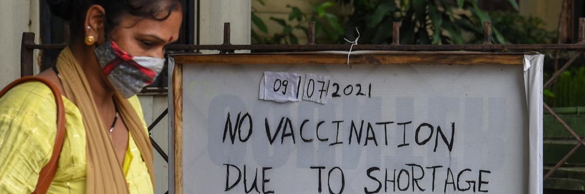 A woman walks past a notice announcing unavailability of Covid-19 vaccine doses.