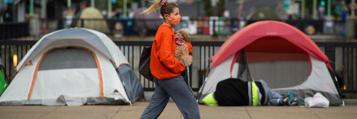 A woman walks past tents used by people experiencing homelessness in Washington, D.C.