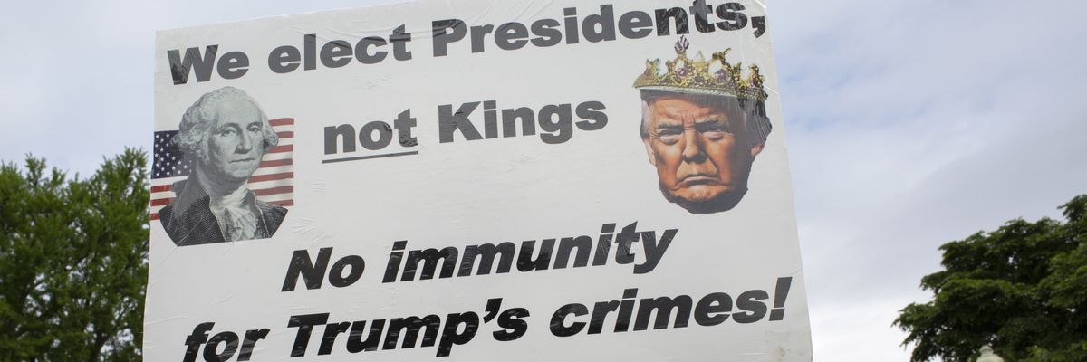 An activist holding a sign reading, "We elect Presidents, Not Kings, No Immunity for Trump's Crimes!"