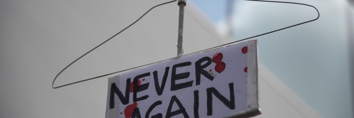 coat hanger sign reading "Never again" to protest abortion ban.