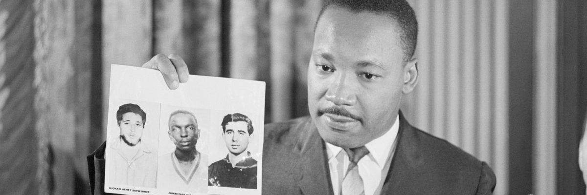 Dr. Martin Luther King Jr. holds a picture of  Michael Schwerner, James Chaney, and Andrew Goodman at press conference. 