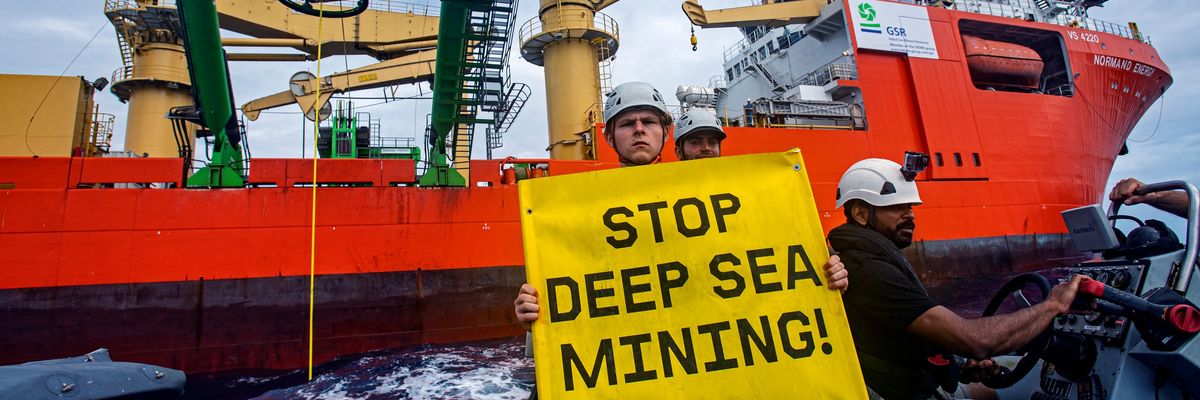 Greenpeace activist holding sign "Stop Deep Sea Mining"