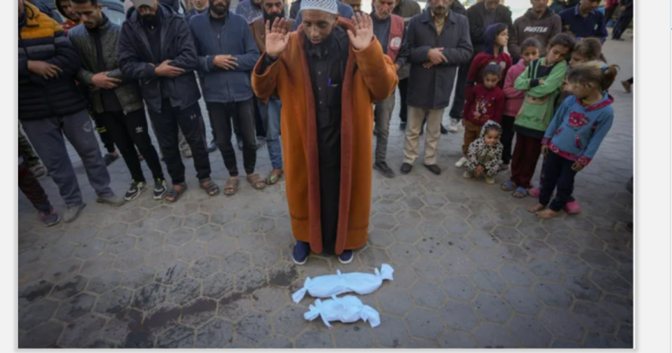 IImam Abu Suaied prays over the bodies of Jumaa and another baby who died at birth in Deir el-Balah 