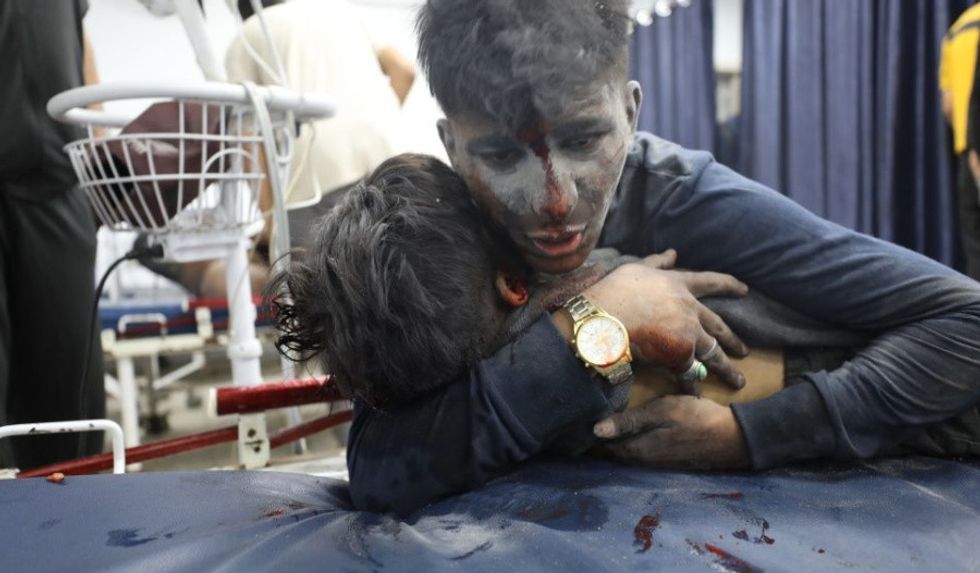 Injured young man hugs body of child killed in Israeli strike on Jabalia refugee camp