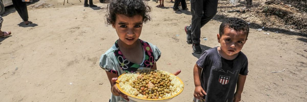 Palestinian children, one holding a plate of food