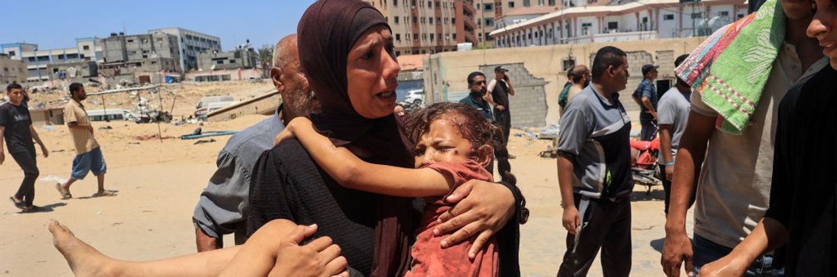 Palestinian woman carries an injured child in Gaza