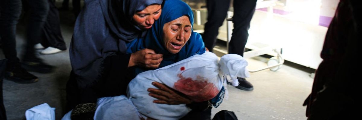 Palestinian women weep as one holds the shrouded body of a child killed by an Israeli strike