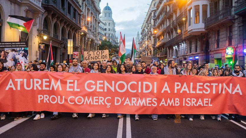 People in Barcelona march with a banner reading "let's stop the genocide in Palestine."