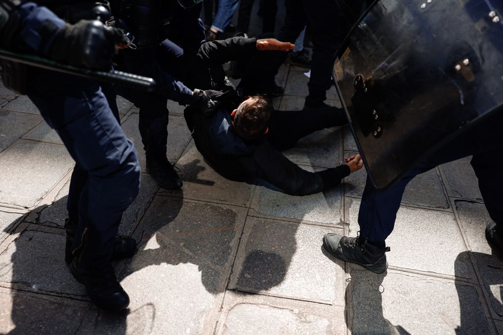 Police officers detain a man demonstrating against French President Emmanuel Macron's proposed pension overhaul in Paris on April 13, 2023.