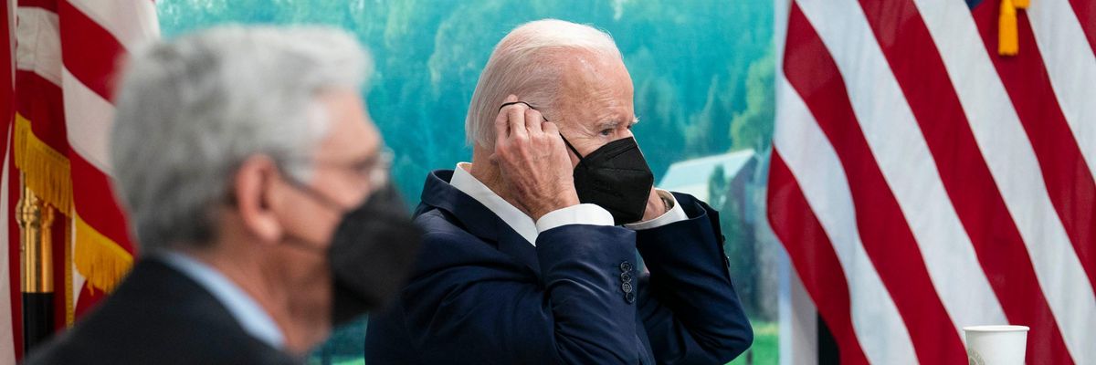 President Joe Biden removes his mask during a meeting