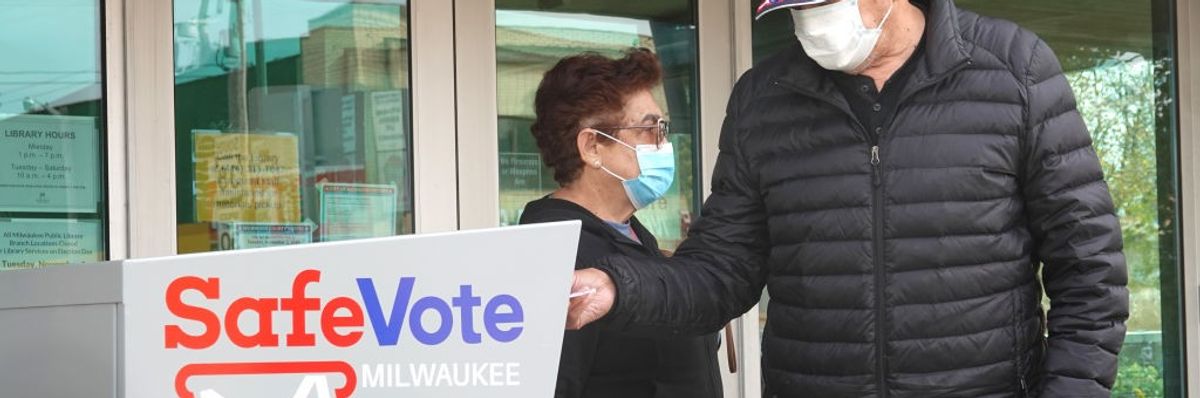 Residents drop ballots in an official drop box 