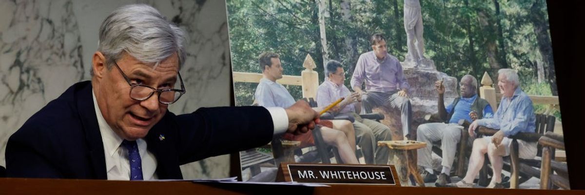 Sheldon Whitehouse points to photo of Clarence Thomas and Harlan Crowe and Leonard Leo