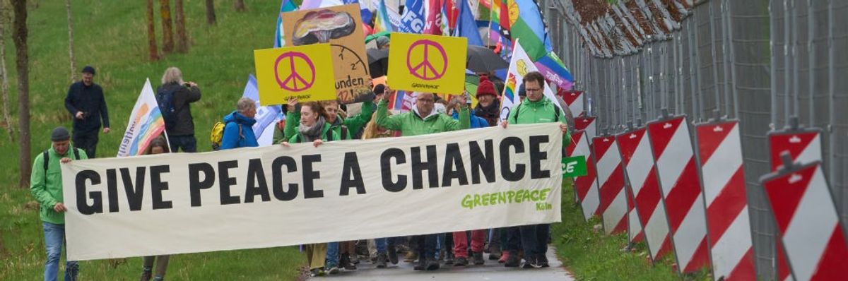 The banner reads: "Give Peace A Chance" outside nuclear base