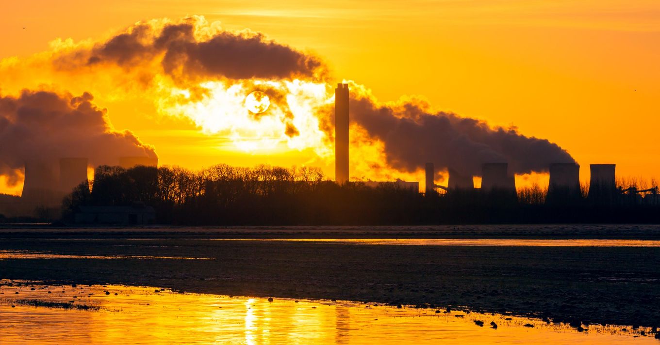 The sun rises behind cooling towers of a power plant in the English village Drax