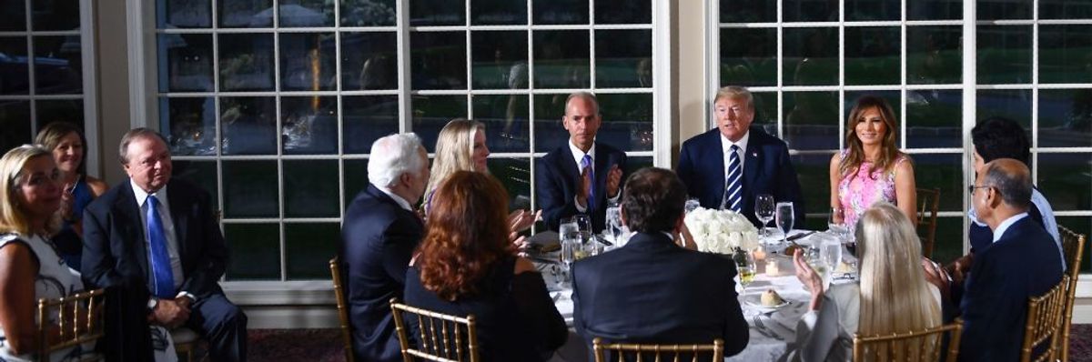Then-President Donald Trump sits with business leaders around a dinner table