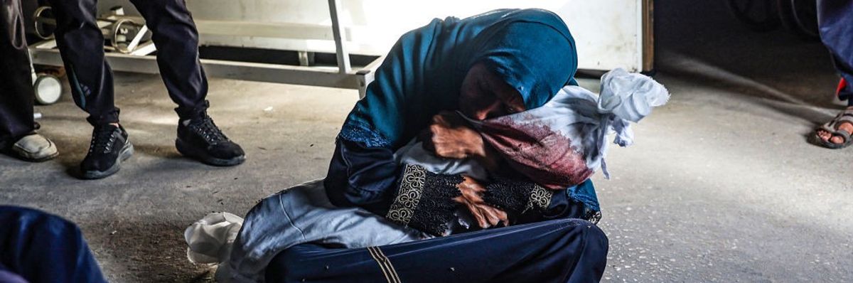 Woman holds the shrouded body of a child killed in Rafah