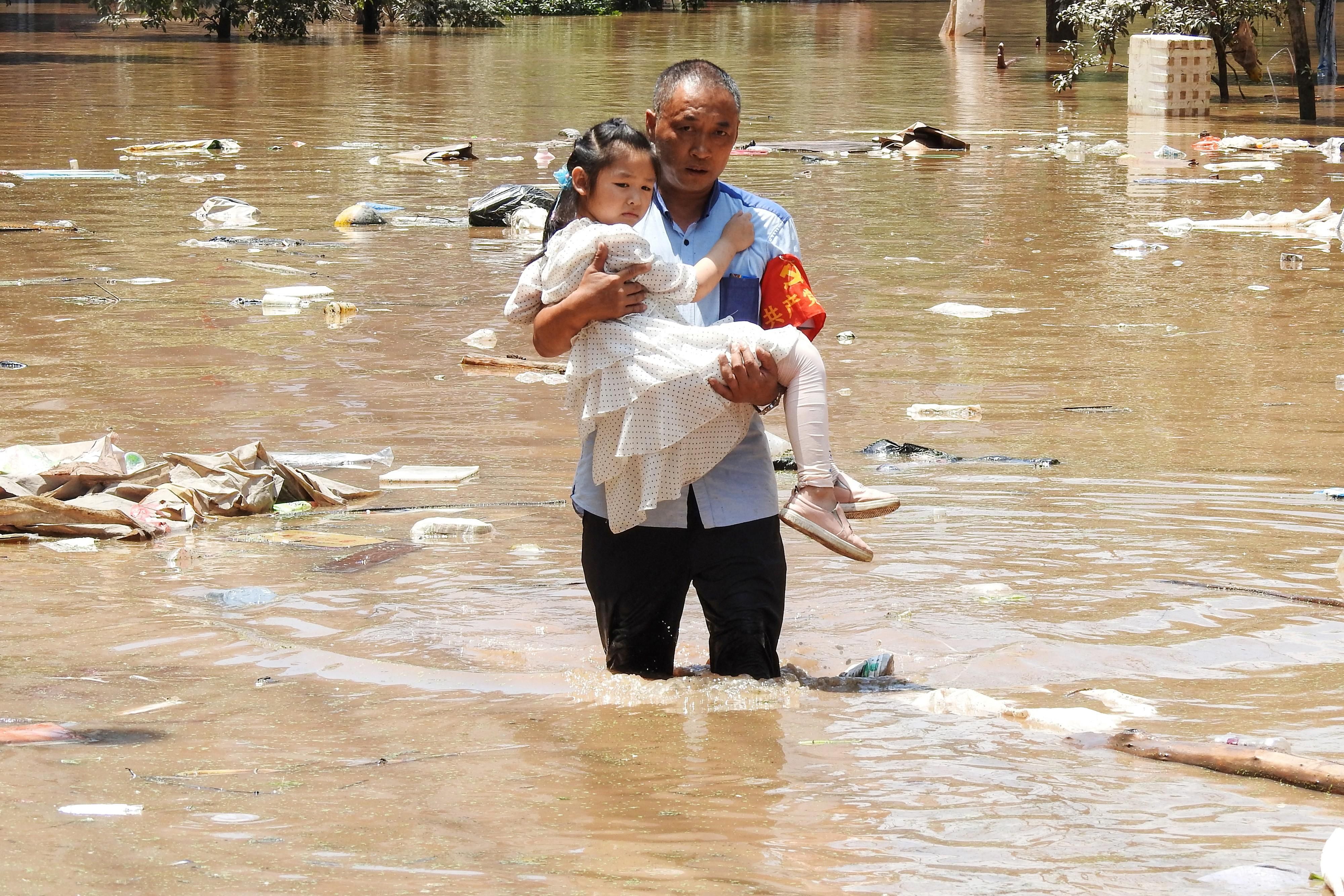 Man carries child through flooded waters